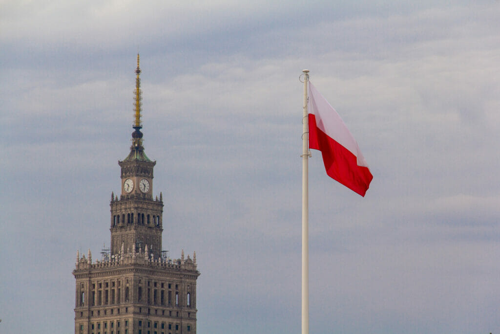 WARSAW, Poland – August 10, 2018: Iconic Palace of Culture and Science (Paac Kultury i Nauki; PKiN), the tallest building in Warsaw, with a Polish flag on a flagpole in the foreground