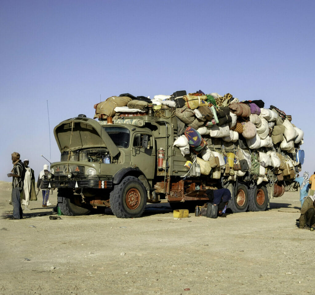 Mondou, Chad - December 8, 2012: The picture was took in the desert of Chad during a morning time, we can see a group of immigrant traveling to another country, they are close to a border, when the truck full of goods break down. December 2012